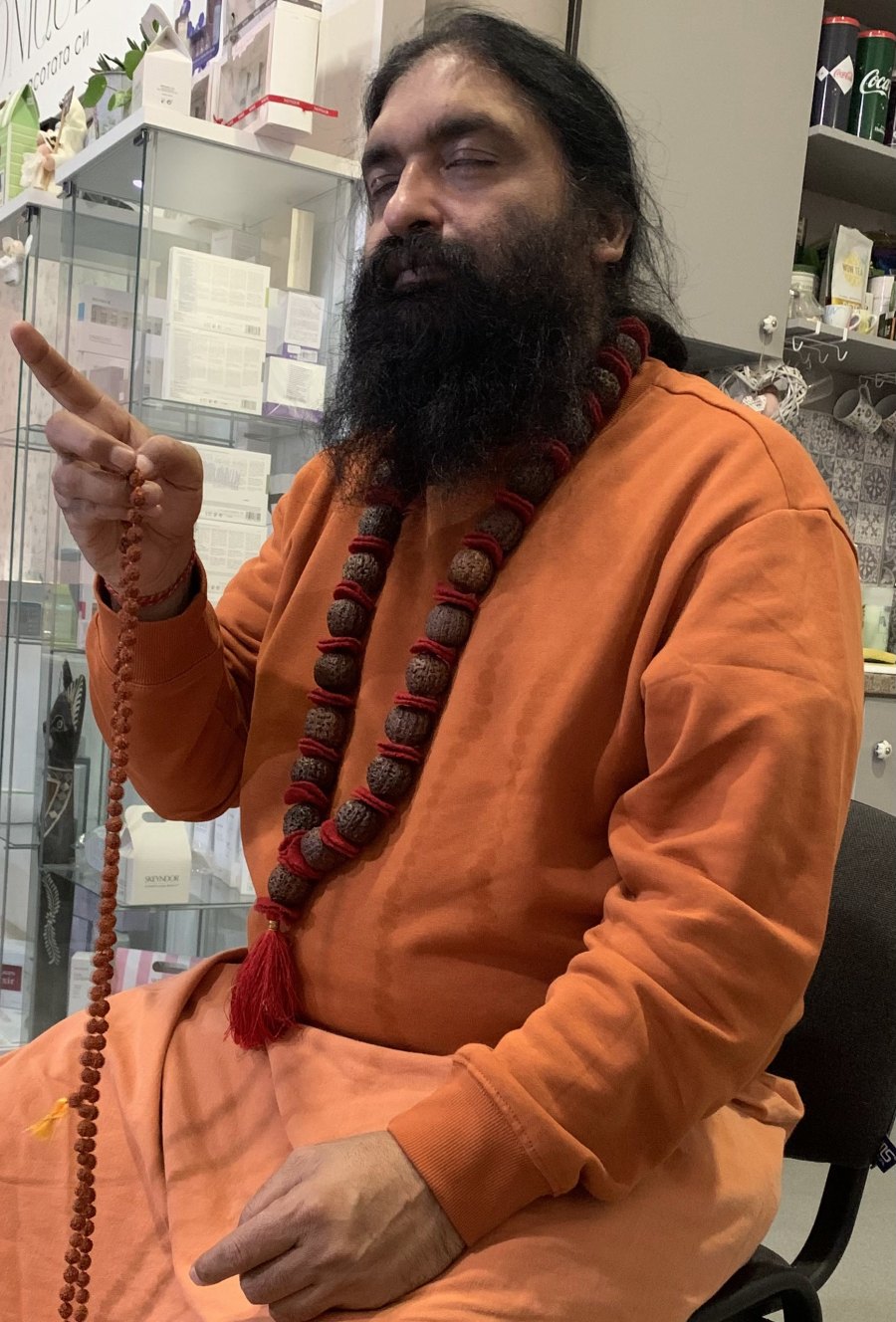 Swami Aditya raising a hand in teaching, holding japa beads